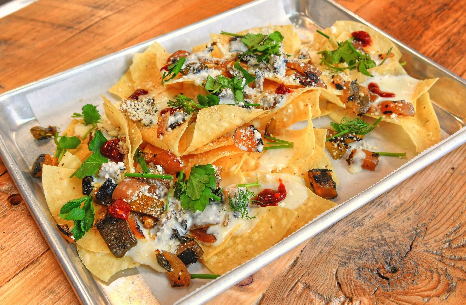 Macho Nachos, crunchy corn tortillas, queso sauce, charred veggies, cotija and herbs, plus  add your favorite slow-cooked meat. CONTRIBUTED BY CHRIS HUNT PHOTOGRAPHY)