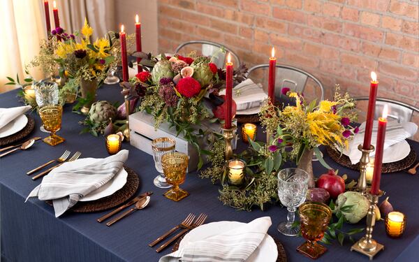 A mixture of fruits, vegetables and flowers create a lovely runners on this table. The woven chargers beneath the scalloped porcelain plates complement the organic accents on the table.