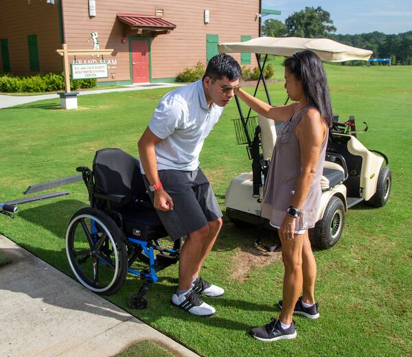 Mak Yost gets help from his mother Faye Yost moving from his wheelchair before working with Bobby Jones golf pro Orlando Rodriguez using adaptive golf equipment like the Solo Rider that helps him stand and hit the golf ball. PHIL SKINNER FOR THE ATLANTA JOURNAL-CONSTITUTION.