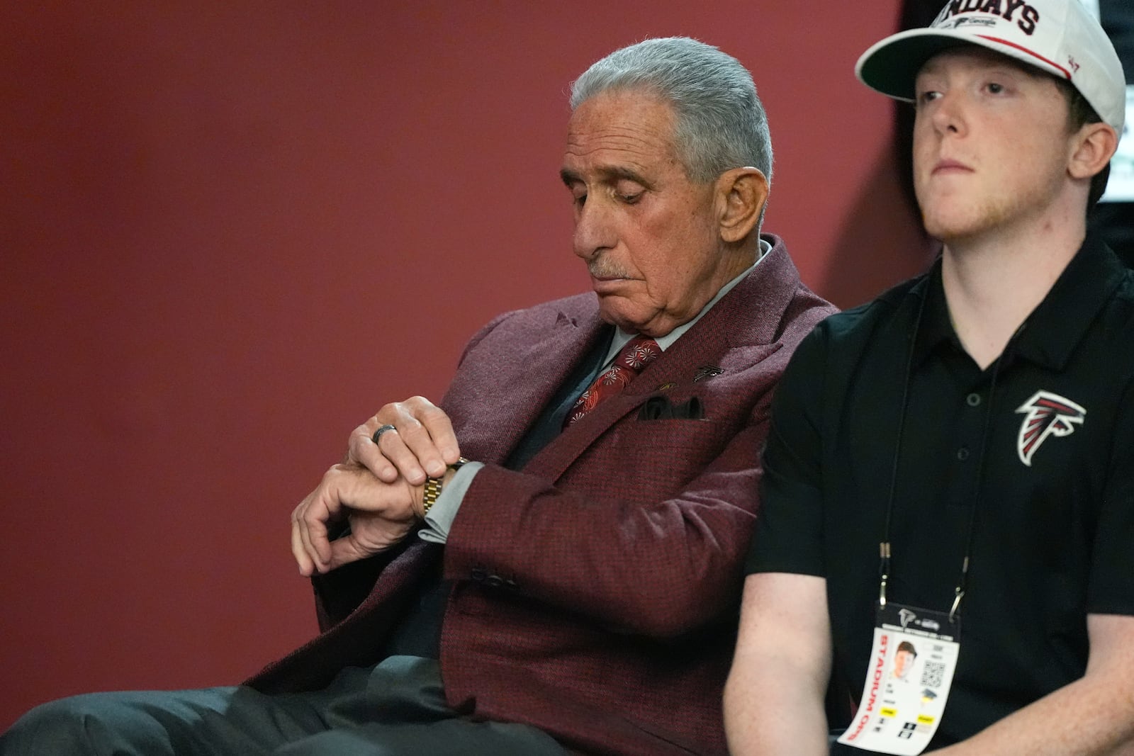 Atlanta Falcons owner Arthur Blank, left, looks at his watch during head coach Raheem Morris' press conference following their loss to the Seattle Seahawks in an NFL football game, Sunday, Oct. 20, 2024, in Atlanta. (AP Photo/ Mike Stewart)