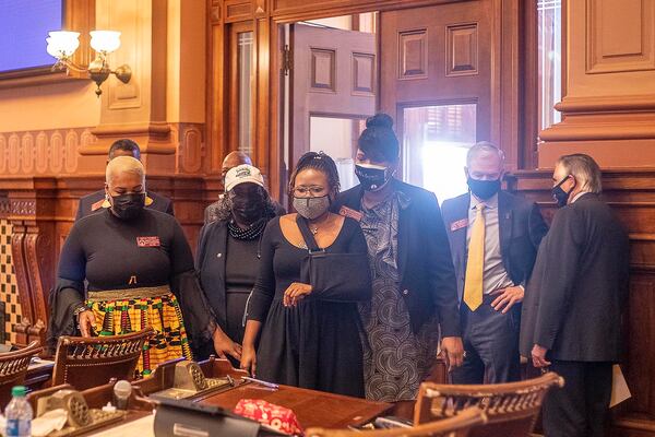 Rep. Erica Thomas (D-Austell), left, Rep. Sandra Scott (D-Rex), second from left and Rep. Debra Bazemore (D-Riverdale), third from right, escort Rep. Park Cannon (D-Atlanta), center, to her seat in the House Chambers at the Georgia State Capitol Building on day 39 of the legislative session in Atlanta, Georgia on Monday, March 29, 2021. (Alyssa Pointer/Atlanta Journal-Constitution/TNS)