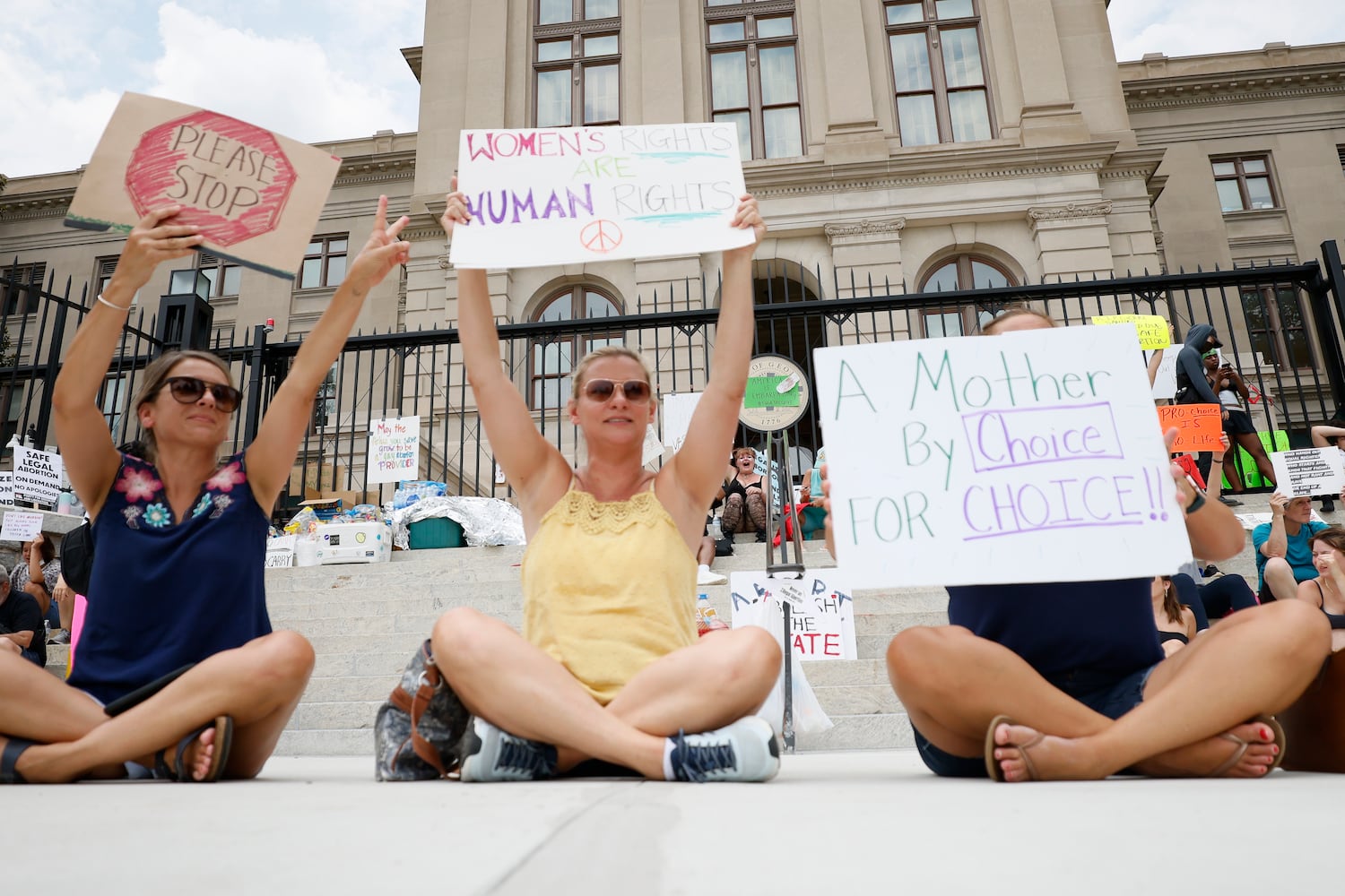 L-R, Misty Whittaker, Maike Caudle, and Casey Key react as a car honk outside the Georgia State Capitol, where abortion rights activists rally to protest the  U.S. Supreme Court's overturning of Roe v Wade. Sunday, June 26, 2022. Miguel Martinez /miguel.martinezjimenez@ajc.com 