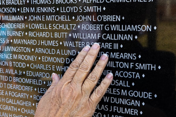 Margo Truett touches the name of her father, Army Maj. William Callinan, on a replica of the Vietnam War Memorial wall at the National Infantry Museum in Columbus on Thursday, March 21, 2024. (Arvin Temkar / arvin.temkar@ajc.com)