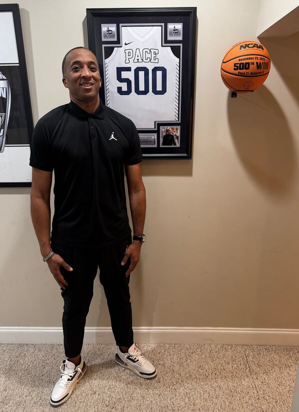 Pace Academy boys basketball coach Sharman White stands by a framed jersey that commemorates his 500th career win, accomplished last season.