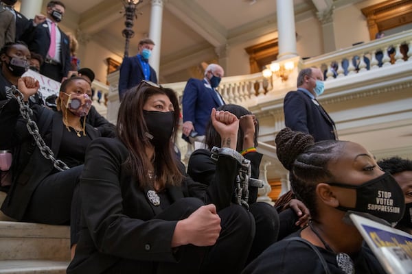 Demonstrators chain themselves together as they stage a sit-in protest against election legislation during Crossover Day. (Alyssa Pointer / Alyssa.Pointer@ajc.com)