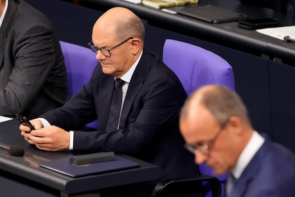 Opposition leader Friedrich Merz of the Christian Democrats delivers a speech while German Chancellor Olaf Scholz, left, checks his mobile phone in the German parliament Bundestag in Berlin, Germany, Wednesday, Nov. 13, 2024. (AP Photo/Markus Schreiber)