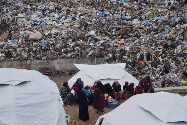 Palestinians displaced by the Israeli air and ground offensive on the Gaza Strip sit in a makeshift tent camp inside a landfill in central Gaza Strip, Friday, March 21, 2025. (AP Photo/Jehad Alshrafi)