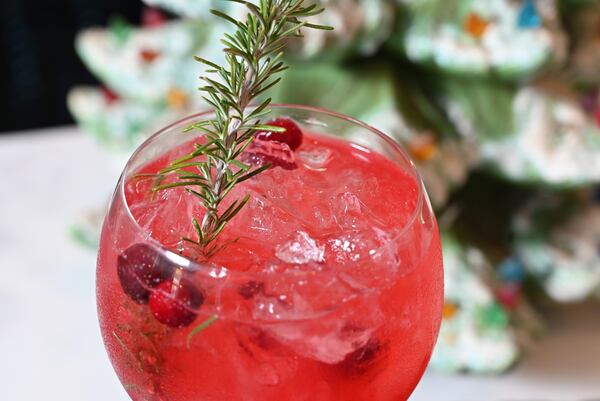 Tiffanie Barriere's Mistletoe Spritz is garnished with fresh cranberries and a sprig of rosemary. (Hyosub Shin / Hyosub.Shin@ajc.com)