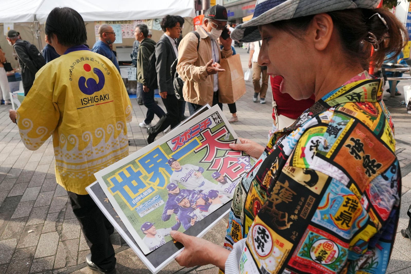 A passerby holds a copy of an extra edition of the Sports Nippon newspaper in Tokyo, Thursday, Oct. 31, 2024, reporting on the Los Angeles Dodgers' victory in the World Series baseball match after the Dodgers defeated the New York Yankees in Game 5 in New York. (AP Photo/Eugene Hoshiko)