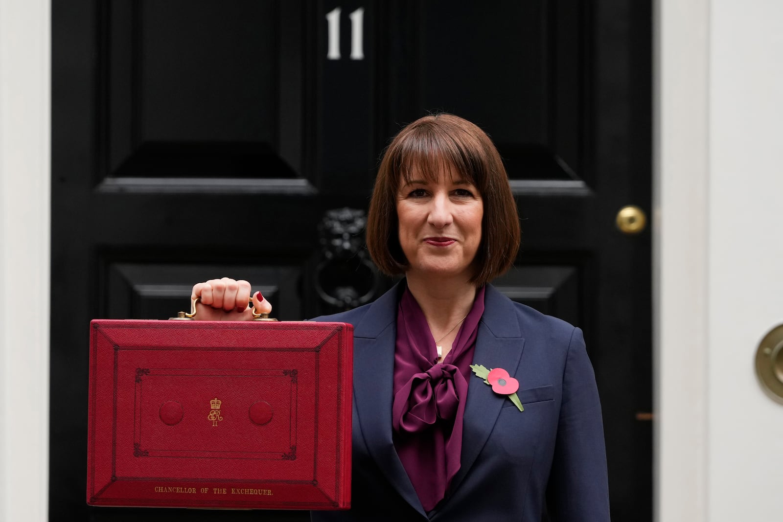 Britain's Chancellor of the Exchequer, Rachel Reeves, holds up the traditional red ministerial box containing her budget speech, as she poses for the media outside No 11 Downing Street, before departing to the House of Commons to deliver the budget in London, Wednesday, Oct. 30, 2024. (AP Photo/Kirsty Wigglesworth)