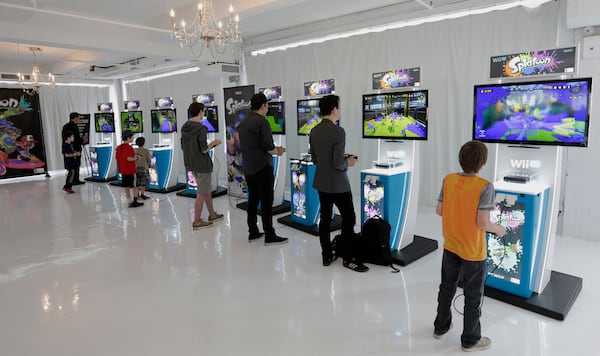 Attendees play the new "Splatoon" video game on a Nintendo Co. Wii U console at a pre-launch event in New York, U.S., on Wednesday, May 6, 2015. Nintendo Co. is scheduled to release earnings figures on May 7. Photographer: Peter Foley/Bloomberg