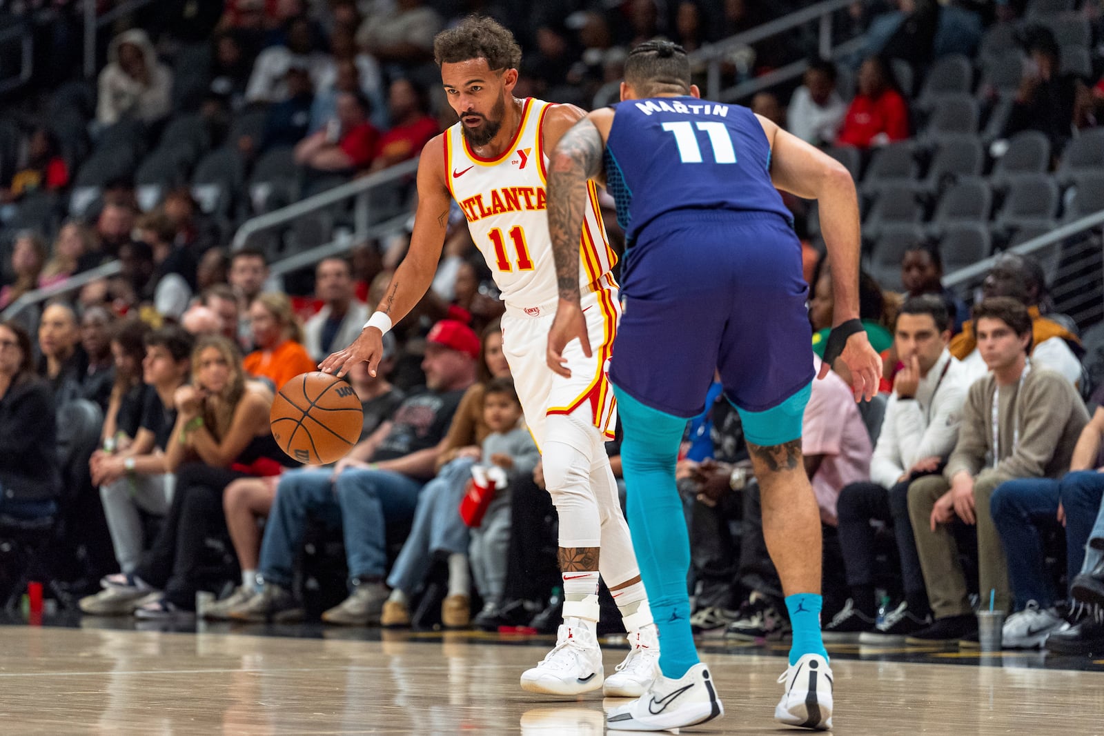 Atlanta Hawks guard Trae Young, left, dribbles while guarded by Charlotte Hornets forward Cody Martin, right, during the first half of an NBA basketball game, Friday, Oct. 25, 2024, in Atlanta. (AP Photo/Jason Allen)