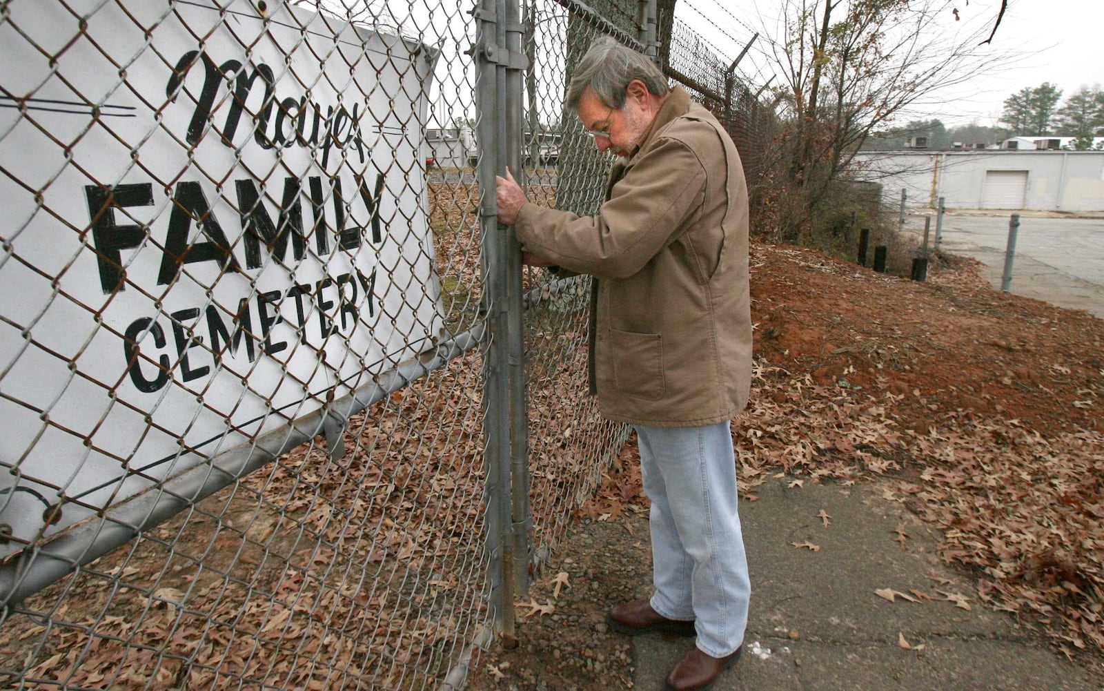 The Mayes Family Cemetery looks out onto the run-down Sprayberry Crossing shopping center and has been swallowed up by commercial development in northern Cobb County. (Johnny Crawford/AJC)