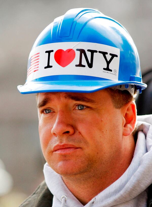 FILE - In this Oct. 11, 2001 file photo,  with an "I Love NY" sticker on his hardhat, New York City firefighter Kevin Bohan pauses at a memorial service near ground zero in New York.  Milton Glaser, the designer who created the "I (HEART) NY" logo and the famous Bob Dylan poster with psychedelic hair, has died. He died Friday, his 91st birthday.AP Photo/Stan Honda, pool, File)