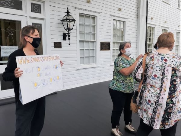 Members of Smart Smyrna, a group of residents opposed to the city's downtown redevelopment plans, stand outside Brawner Hall during an open house there Thursday night. City officials unveiled blueprints for the downtown overhaul during the open house. (Matt Bruce/For the AJC)