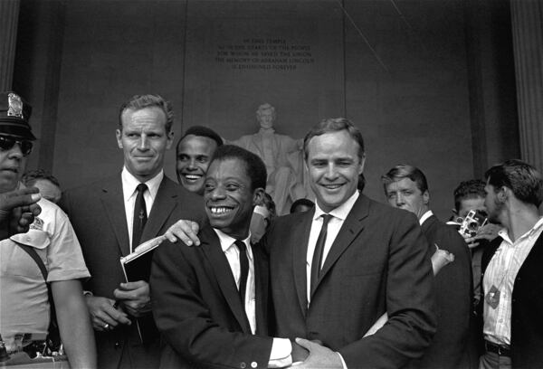 Actor Marlon Brando (right) poses with his arm around James Baldwin, author and civil rights leader, in front of the Lincoln statue at the Lincoln Memorial on Aug. 28, 1963, during the March on Washington demonstration ceremonies that followed the mass parade. Posing with them are actors Charlton Heston (left) and Harry Belafonte. AP PHOTO