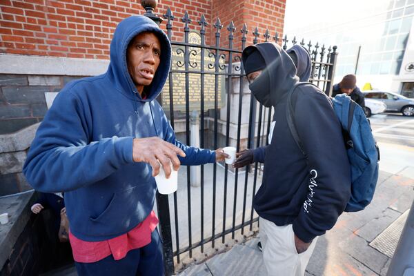 Church employee Frederick Price hands a cup of coffee to someone outside the Catholic Shrine of the Immaculate Conception as they prepare to open their doors for the morning sandwich and snack ministry program. The church serves 200-300 people sandwiches, water, and coffee for those in need each weekday.
Miguel Martinez /miguel.martinezjimenez@ajc.com