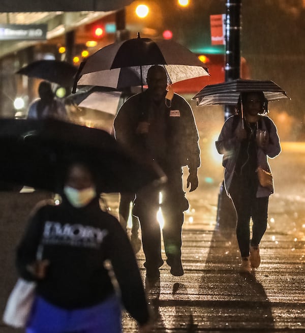 Umbrellas are up along West Peachtree Street at Linden Avenue as rain comes down Thursday morning in downtown Atlanta.