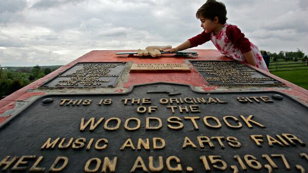 FILE - This May 15, 2008 file photo shows Emma Cenholt, 3, of Trumbull, Conn., playing on a memorial at the site of the Woodstock Music and Arts Fair in Bethel, N.Y. Woodstock 50 is less than four months away, but tickets for the event are still unavailable. Tickets for the three-day festival on Aug. 16-18 were supposed to go on sale Monday. The festival released a statement Thursday, saying: “Woodstock 50 has delayed its on sale while we refine logistical plans.”