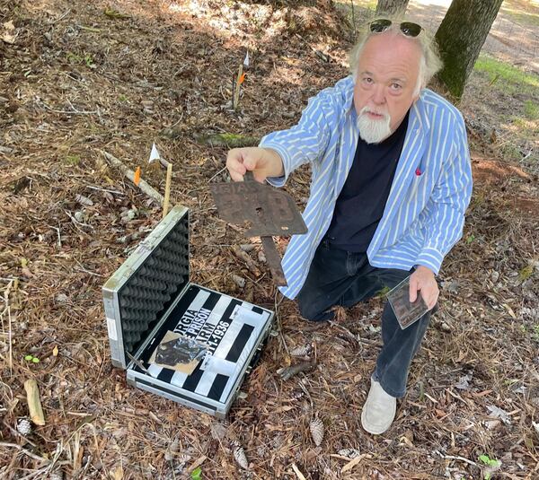 Edwin C. Atkins, whose great-grandfather was the chaplain at the Georgia State Prison Farm, shows a rusted license plate manufactured at the prison that once marked a prisoner's grave. Photo by Bill Torpy