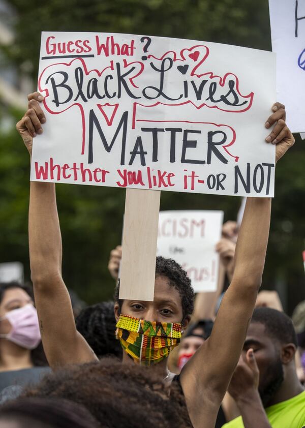 A protestor displays a sign during the 10th day of protests in Atlanta Sunday. ALYSSA POINTER / ALYSSA.POINTER@AJC.COM