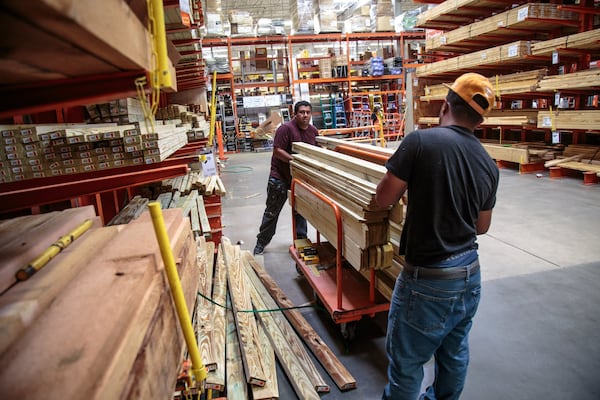 Jose Campos (L) and Brian Mejia load up their cart with lumber at the Cumberland Parkway Home Depot in Atlanta recently. STEVE SCHAEFER / SPECIAL TO THE AJC