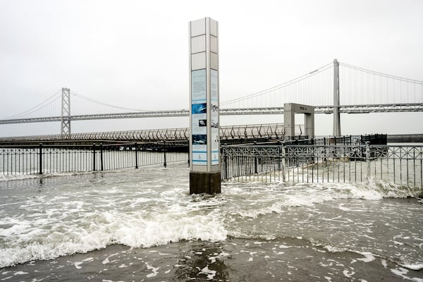 Water from the San Francisco Bay spills onto the Embarcadero in San Francisco on Saturday, Dec. 14, 2024, as a result of high tides and storm-driven waves. (AP Photo/Noah Berger)