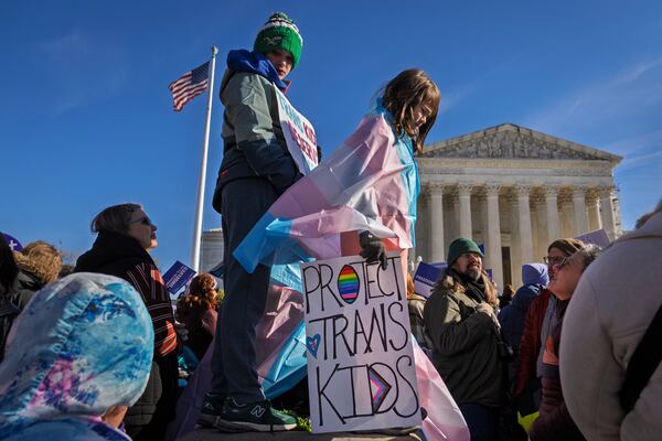 Nate, 14, left, and Bird, 9, right, whose parents asked not to use their last names, hold signs and transgender pride flags as supporters of transgender rights rally by the Supreme Court, Wednesday, Dec. 4, 2024, in Washington, while arguments are underway in a case regarding a Tennessee law banning gender-affirming medical care for transgender youth. (AP Photo/Jacquelyn Martin)