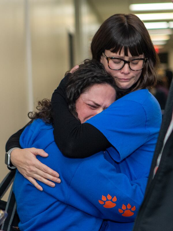 Amy Lund, left, a pre-K teacher and parent at Spalding Drive Elementary, is supported after the Fulton County Board of Education votes to close the two elementary schools on Thursday, Feb 20, 2025. (Jenni Girtman for The Atlanta Journal-Constitution)