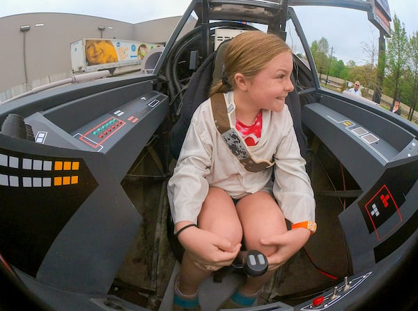 Reese Hagler, 8, sits in the cockpit of the near life-like replica of an X-Wing Starfighter from Star Wars at Embry Village shopping center in Embry Hills on Saturday, April 16, 2022. (Steve Schaefer / steve.schaefer@ajc.com)