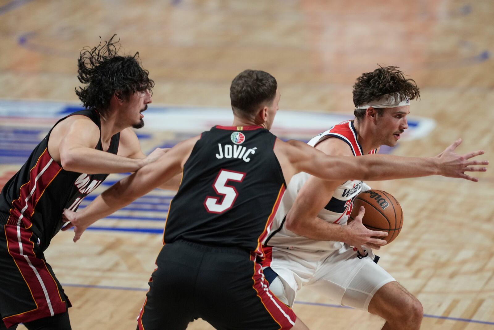 Washington Wizards Corey Kispert, right, drives to the basket against Miami Heat Nikola Jović (5) and Jaime Jaquez Jr. during the first half of an NBA basketball game, at the Mexico Arena in Mexico City, Saturday, Nov. 2, 2024. (AP Photo/Fernando Llano)