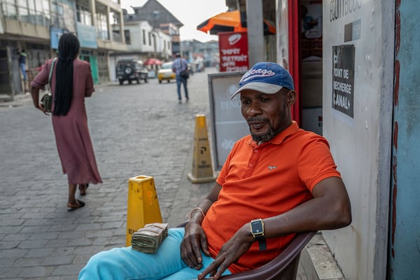 Currency exchanger Karu Lievain waits for customers in downtown Goma, Democratic Republic of Congo, Thursday, Feb. 27, 2025, one month after Rwanda-backed M23 rebels captured the city. (AP Photo/Moses Sawasawa)