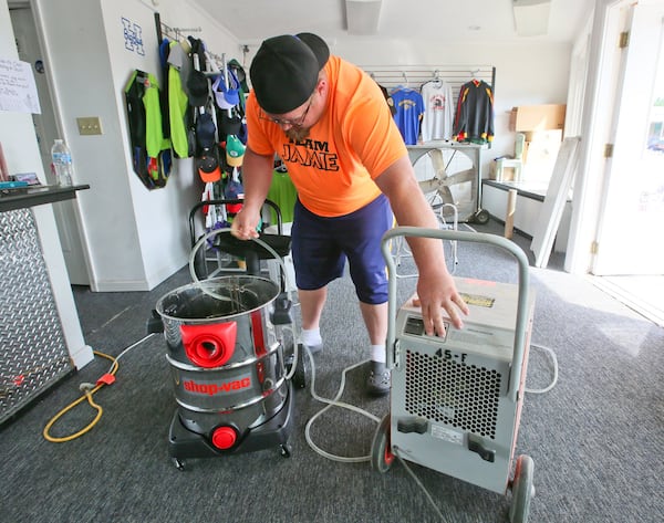 Josh Bowling checks his dehumidifier as he cleans up after flooding at Sign Addiction, owned by his wife Jamie, on Main St. in Hamilton, Friday, June 3, 2016. GREG LYNCH / STAFF