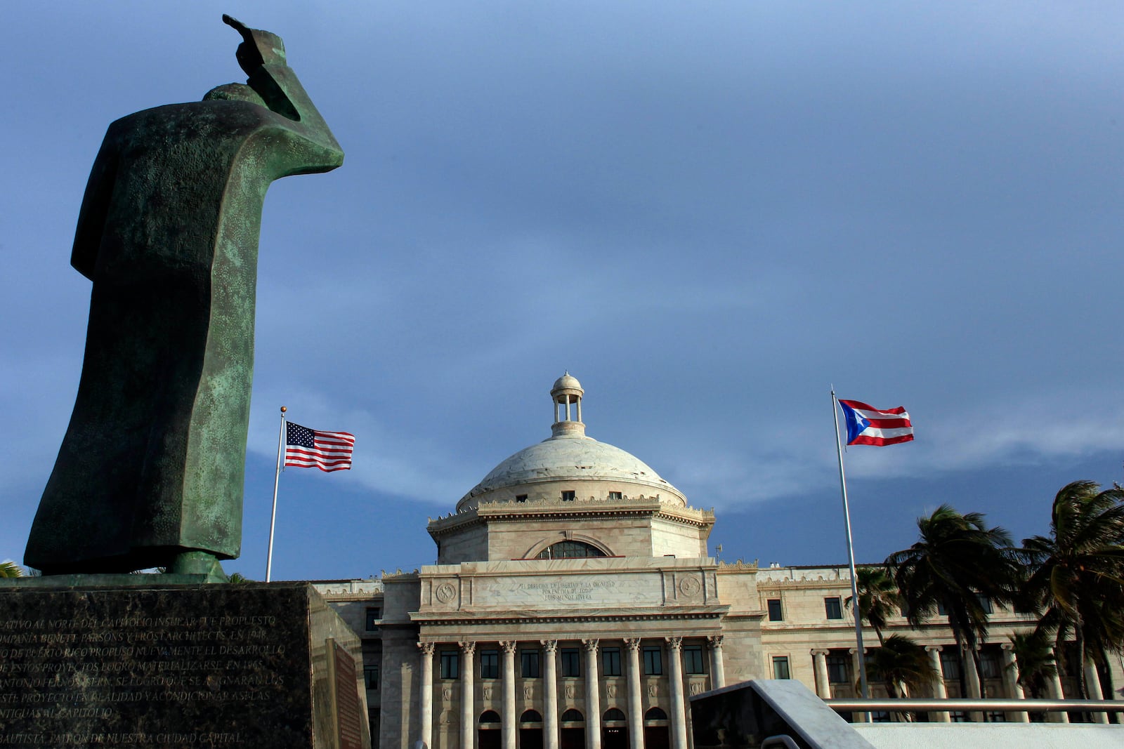 FILE - A bronze statue of San Juan Bautista stands in front the Capitol building flanked by U.S. and Puerto Rican flags, in San Juan, Puerto Rico, Sept. 30, 2016. (AP Photo/Ricardo Arduengo, File)