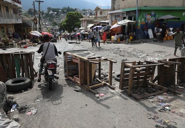 A motorcycle taxi driver crosses a barricade set up by residents, in Port-au-Prince, Haiti, Thursday, Nov. 14, 2024. (AP Photo/Odelyn Joseph)