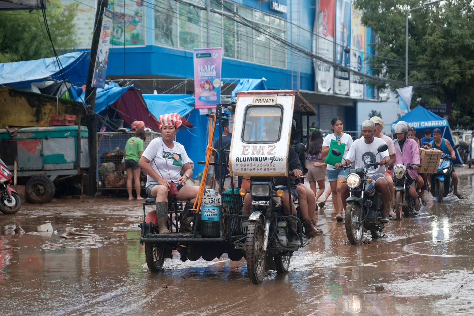 Residents pass by a muddied road after floods caused by Tropical Trami hit Polangui town, Albay province, Philippines Wednesday, Oct. 23, 2024. (AP Photo/John Michael Magdasoc)