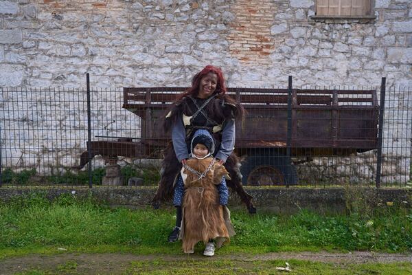 Vasiliki Pergada poses with her four year old daughter Panagiota for a portrait, dressed in animal skins and heavy bronze bells, as part of carnival celebrations in Distomo, a village in central Greece, on Monday, March 3, 2025. (AP Photo/Petros Giannakouris)