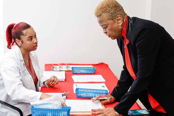 (Left to right) Student pharmacist Daria Gibson assists  Conference of National Black Churches president Jacqui Burton with paperwork before receiving a COVID-19 shot at a vaccine clinic hosted by the Conference of National Black Churches at Morris Brown College on Tuesday, Oct. 10, 2023. (Natrice Miller/ Natrice.miller@ajc.com)