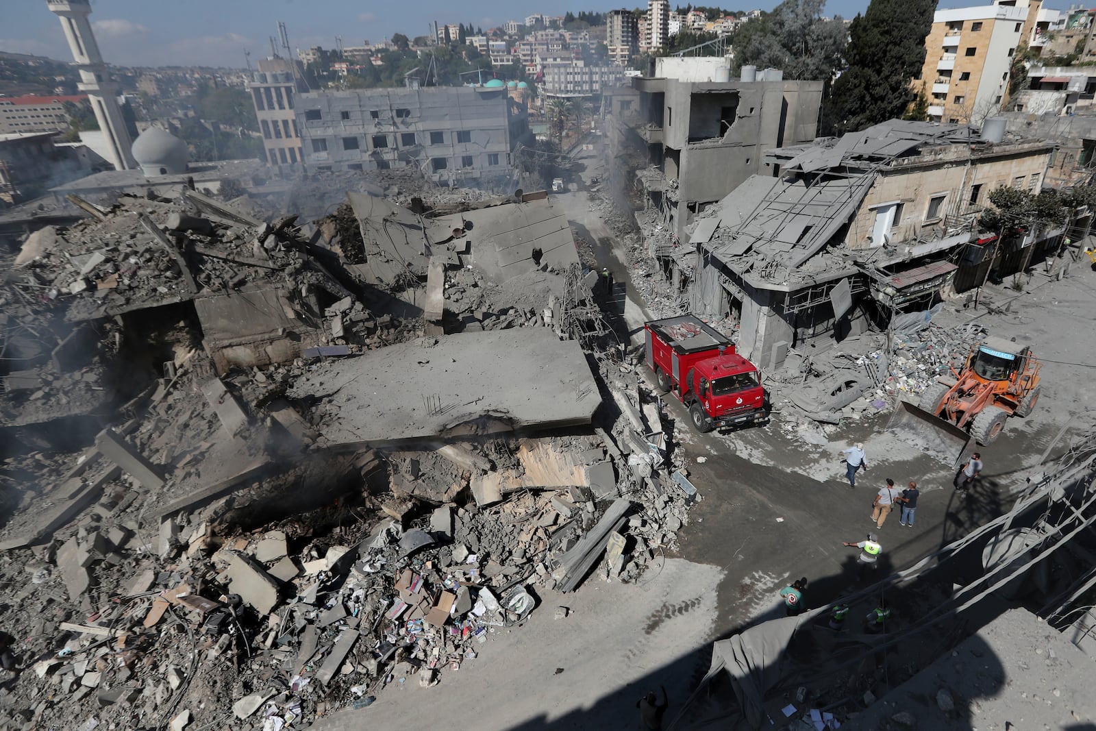 Hezbollah rescue workers use a bulldozer to remove the rubble of destroyed buildings on a commercial street that was hit Saturday night by Israeli airstrikes, in Nabatiyeh town, south Lebanon, Sunday, Oct. 13, 2024. (AP Photo/Mohammed Zaatari)