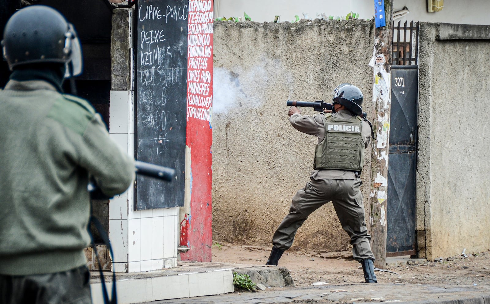 A police officer aims his weapon at protesters in Maputo, Mozambique, Thursday, Nov. 7, 2024. Protesters dispute the outcome of the Oct. 9 elections that saw the ruling Frelimo party extend its 49-year rule. (AP Photo/Carlos Uqueio)