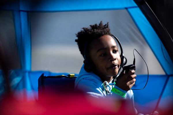 Elias speaks to his teacher using a walkie-talkie headset in Smyrna on Saturday, Dec. 5, 2020. Tracey Clark has been leading an experiential learning activity in her neighborhood cul-de-sac where students learn together while socially distanced in tents. (Rebecca Wright for The Atlanta Journal-Constitution) 