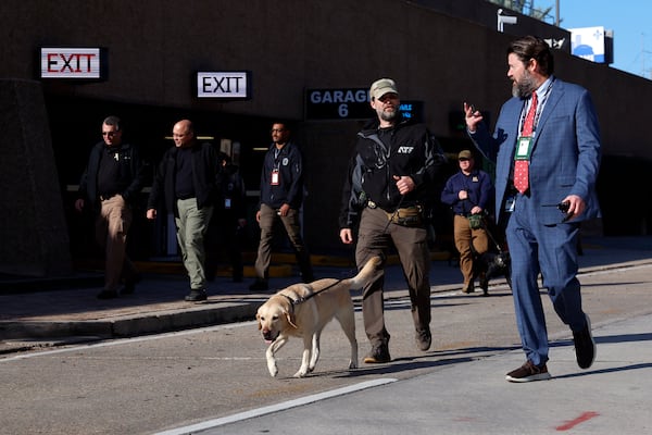 Security with bomb sniffing dogs patrol the area around the Superdome ahead of the Sugar Bowl NCAA College Football Playoff game, Thursday, Jan. 2, 2025, in New Orleans. (AP Photo/Butch Dill)