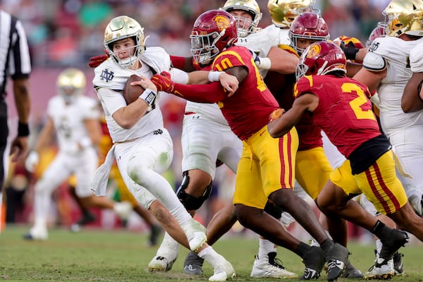 Notre Dame quarterback Riley Leonard, left, is sacked by Southern California defensive end Jamil Muhammad, center, during the second half of an NCAA college football game Saturday, Nov. 30, 2024, in Los Angeles. (AP Photo/Ryan Sun)