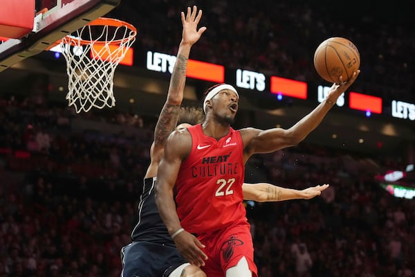 Miami Heat forward Jimmy Butler (22) spins, shoots and makes a basket without looking at the basket as Dallas Mavericks center Dereck Lively II, back left, defends during the second half of an NBA basketball game, Sunday, Nov. 24, 2024, in Miami. (AP Photo/Jim Rassol)