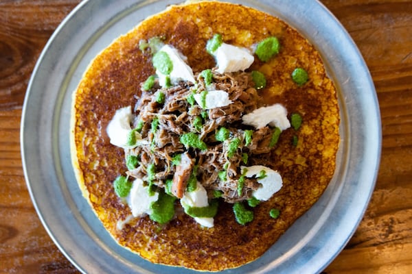 Arepa Mia was the only Latin American restaurant to make the 2023 Michelin Atlanta guide. Pictured is the eatery's cachapa pernil topped with roasted pork cooked in mojo sauce, caramelized onion, cilantro sauce and guayanes cheese. (Henri Hollis/AJC) 