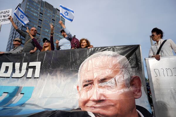 Supporters of Israel's Prime Minster Benjamin Netanyahu, seen in poster, gather outside a court in Tel Aviv, Israel, Tuesday, Dec. 10, 2024 as Netanyahu is set to take the stand in his long-running trial on corruption charges. (AP Photo/Ariel Schalit)