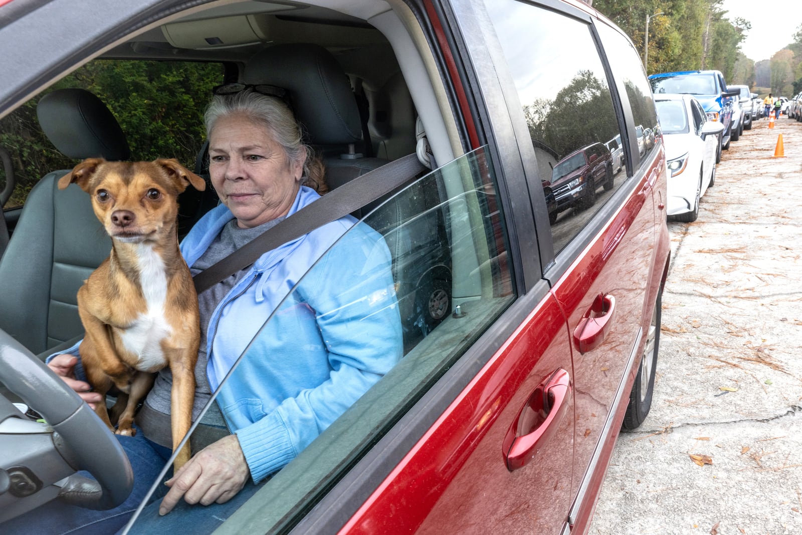 Leigha Woodard and her dog Bo wait in line during the Reflections of Trinity weekly food distribution in Powder Springs on Saturday, Nov. 12, 2022. (Photo: Steve Schaefer / steve.schaefer@ajc.com)