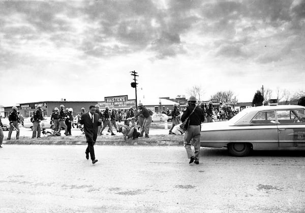 In this March 7, 1965, file photo, march leader Hosea Williams, left, leaves the scene as state troopers break up the civil rights voter registration march in Selma, Ala., and put John Lewis, center, of the Student Non-violent Coordinating Committee on the ground. Hundreds gathered Sunday, March 3, 2013 for a brunch with Vice President Joe Biden, and thousands were expected Sunday afternoon to march across this bridge in Selma's annual Bridge Crossing Jubilee. The event commemorates the "Bloody Sunday" beating of voting rights marchers by state troopers as they began a march to Montgomery in March 1965. The 50-mile march prompted Congress to pass the Voting Rights Act that struck down impediments to voting by African-Americans and ended all-white rule in the South. (AP Photo/File)