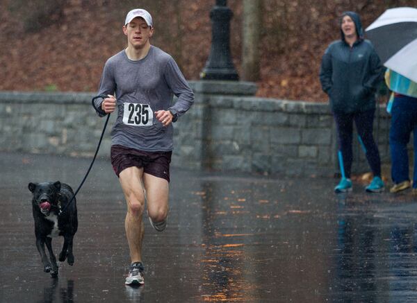 Thomas Clarke and his dog Finn are the first team to cross the finish line during the Piedmont Park Conservancy's 5th Year Anniversary of the Doggie Dash and 5K in Piedmont Park on Sunday, March  11, 2018. Heavy rain continued through the morning.   STEVE SCHAEFER / SPECIAL TO THE AJC