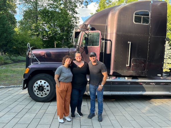 Snellville truck driver Jess Graham, middle, poses in front of her truck, "Black Widow," with Jenni Ruiz, Transfix senior marketing manager, content & community and  celebrity handyman Jason Cameron. Graham was winner of the "TransFIX My Rig" cab makeover. Photo courtesy of Transfix